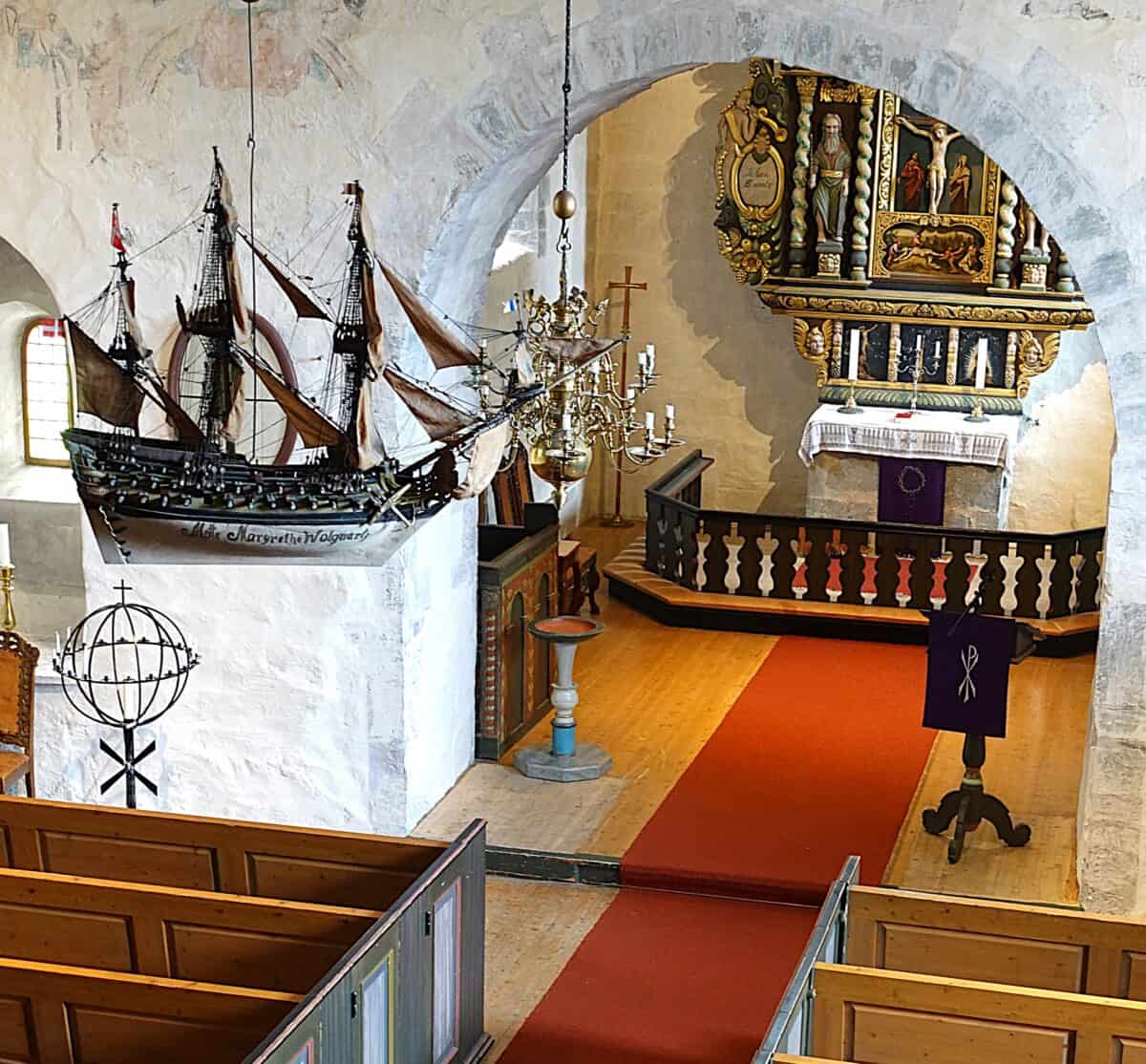 From the nave and choir of Byneset church, with a traditional sailing ship hanging from the ceiling, as well as a hanging chandelier.