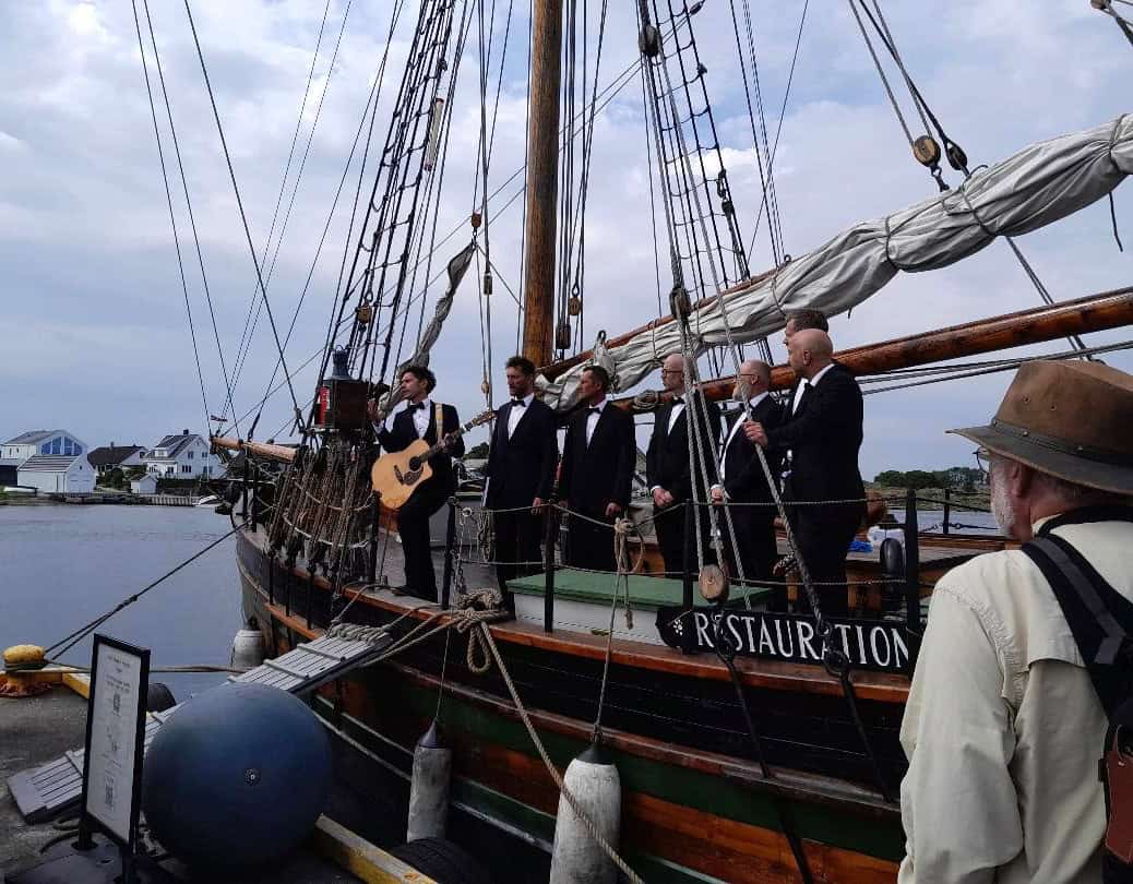 DUring preparations for the great 200 year's anniversary for Norwegian emigration to USA and Canada, the replica sloop Restauration was visited by an American study group in 2024. The local young men's choir sang shanties and songs for the visitors.